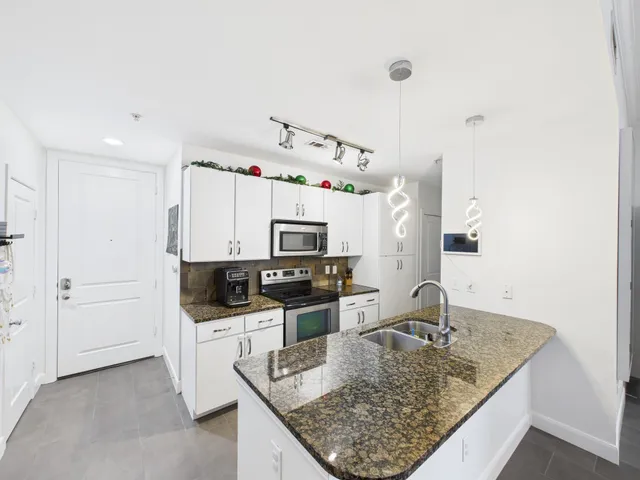 a kitchen with granite countertop a sink a stove and a wooden floor