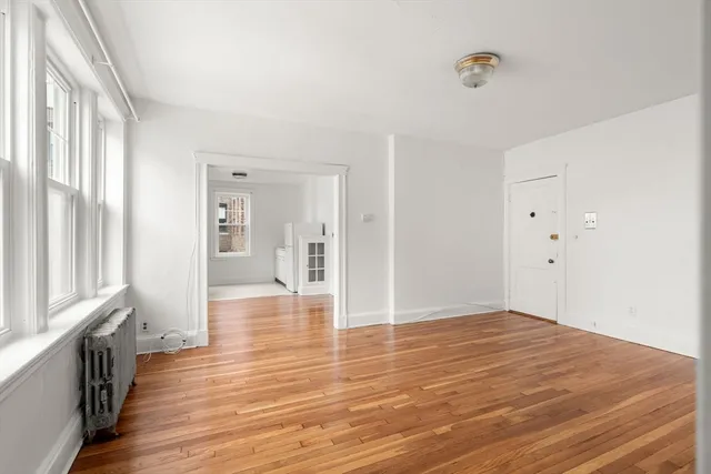 a view of an empty room with wooden floor and a window