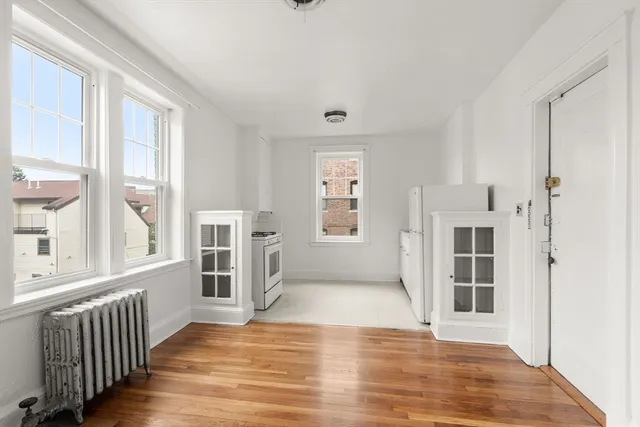 wooden floor in an empty room with a window and a kitchen