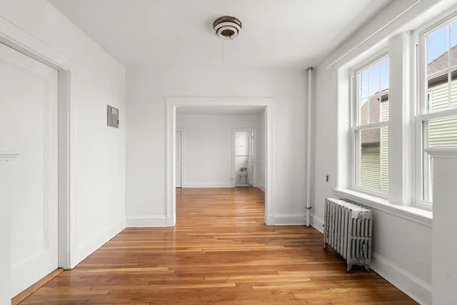 a view of a hallway with wooden floor and a window