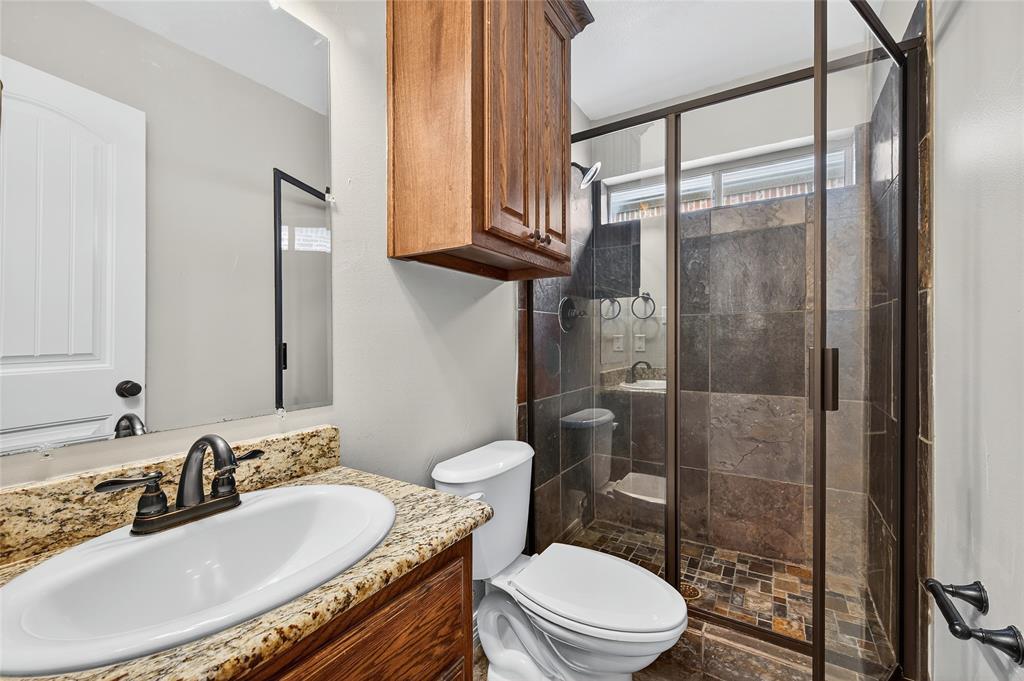 4814 Hilre Drive Sherman, TX 75092 - Photo 22 of 27 a bathroom with a granite countertop sink toilet a mirror and shower