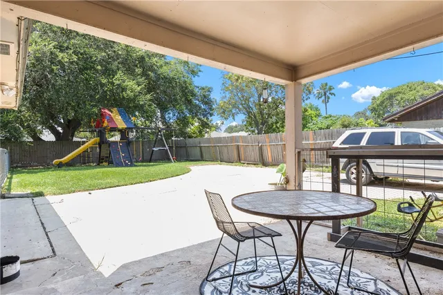 a view of a patio with a table chairs and a small yard