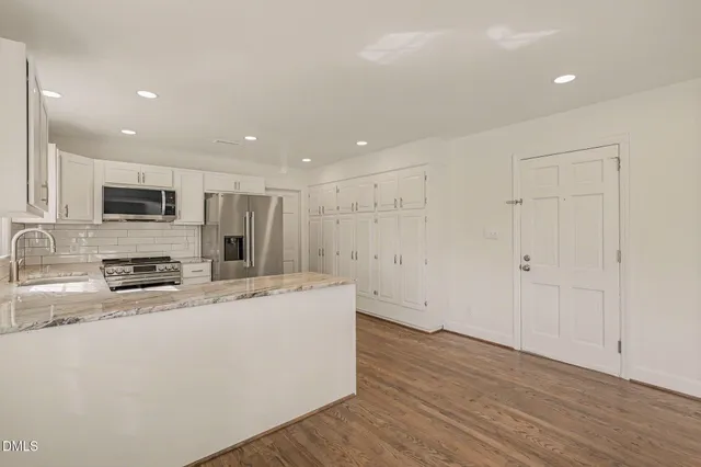a kitchen with stainless steel appliances a refrigerator sink and white cabinets