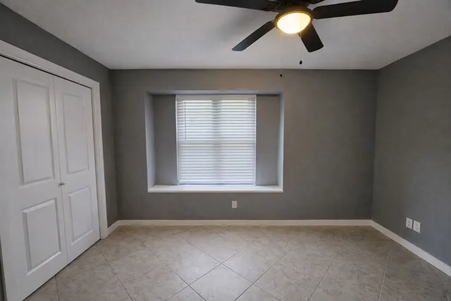 an empty room with a window and a ceiling fan