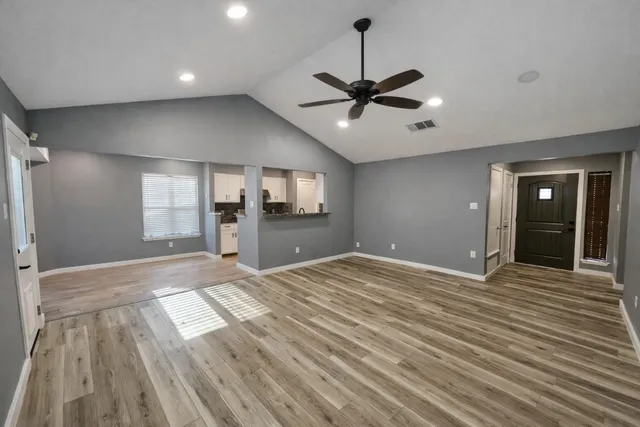 a view of empty room with wooden floor and fan