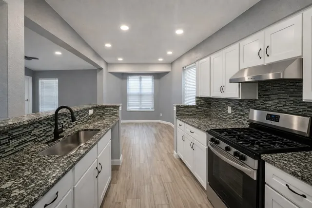 a kitchen with a sink stove top oven and cabinets