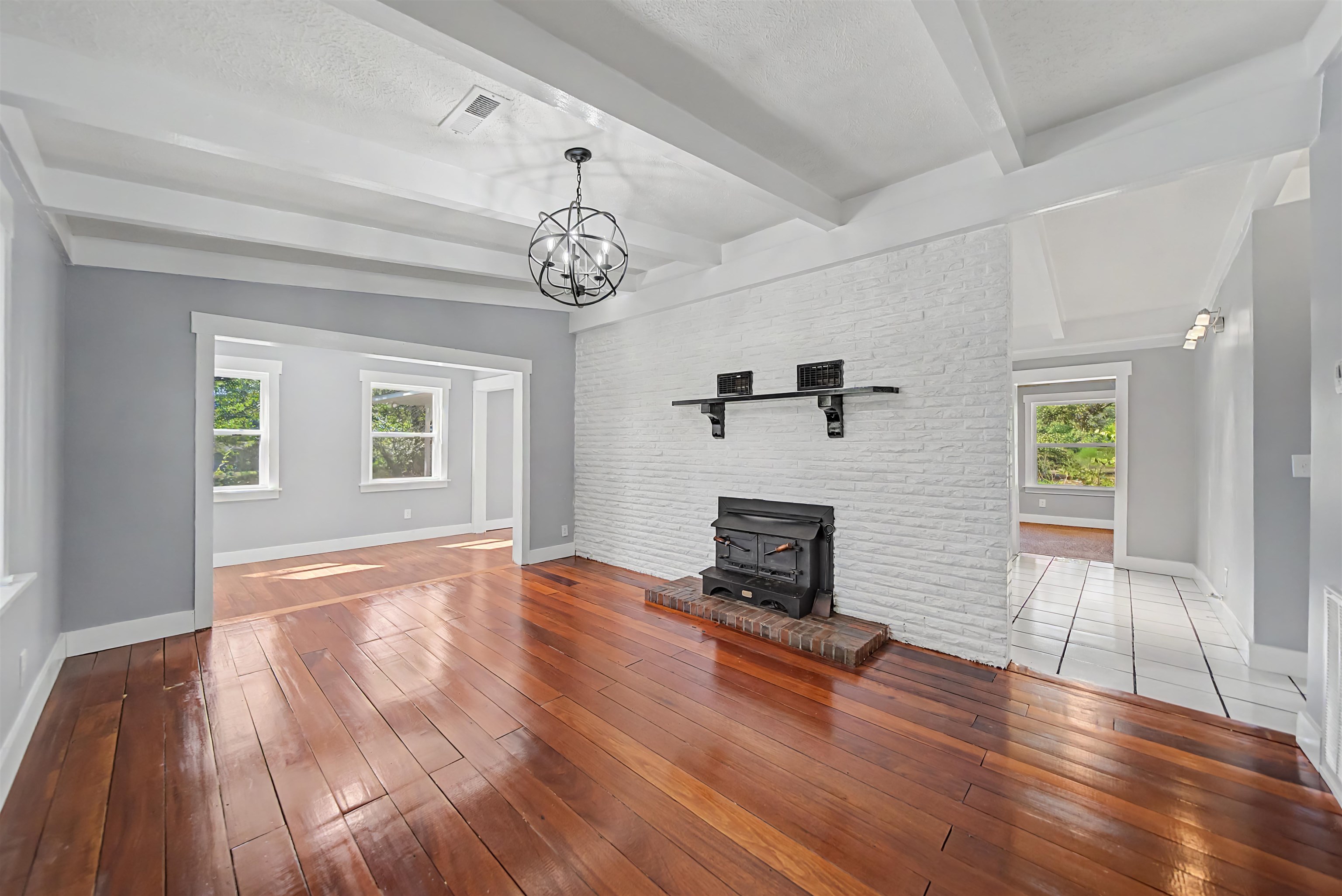 7437 Highway 45 Ramer, TN 38367 - Photo 19 of 36 Exposed ceiling beams, wood-finish flooring, brick-faced fireplace with hearth, and an ornamental chandelier