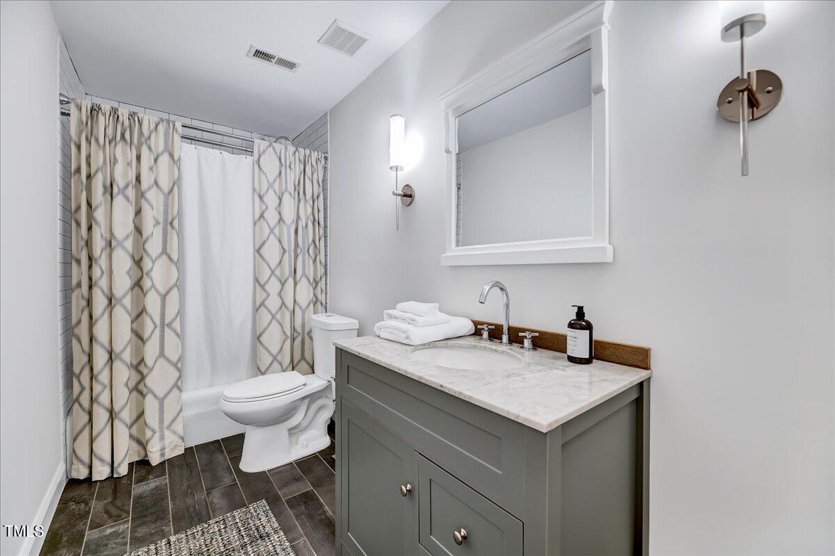 11313 Rumshill Road Raleigh, NC 27614 - Photo 31 of 55 a bathroom with a granite countertop sink a toilet and a mirror