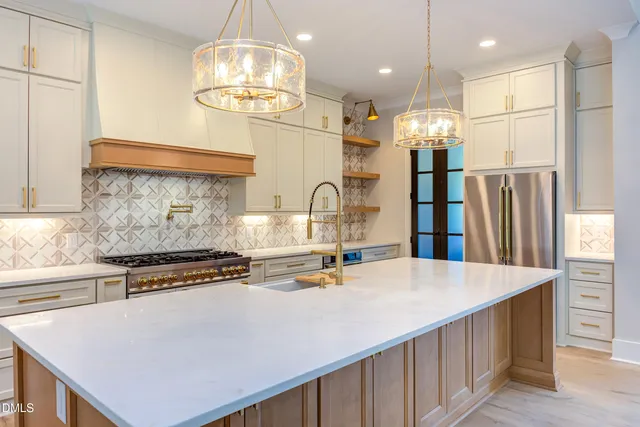 a kitchen with kitchen island granite countertop a stove a sink a refrigerator and a refrigerator