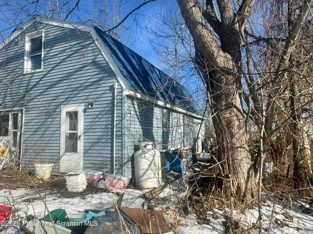 a backyard of a house with table and chairs and potted plants
