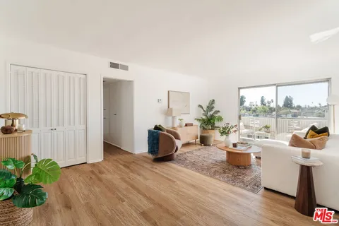 a living room with furniture a large window and wooden floor