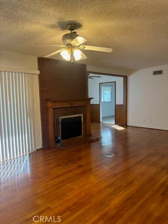 a view of a livingroom with a fireplace a chandelier and wooden floor