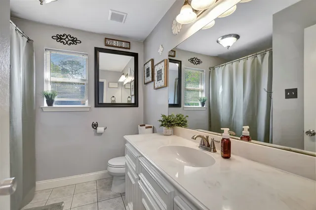a bathroom with a granite countertop sink a toilet a mirror and shower