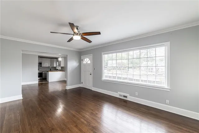 a view of an empty room with window and wooden floor