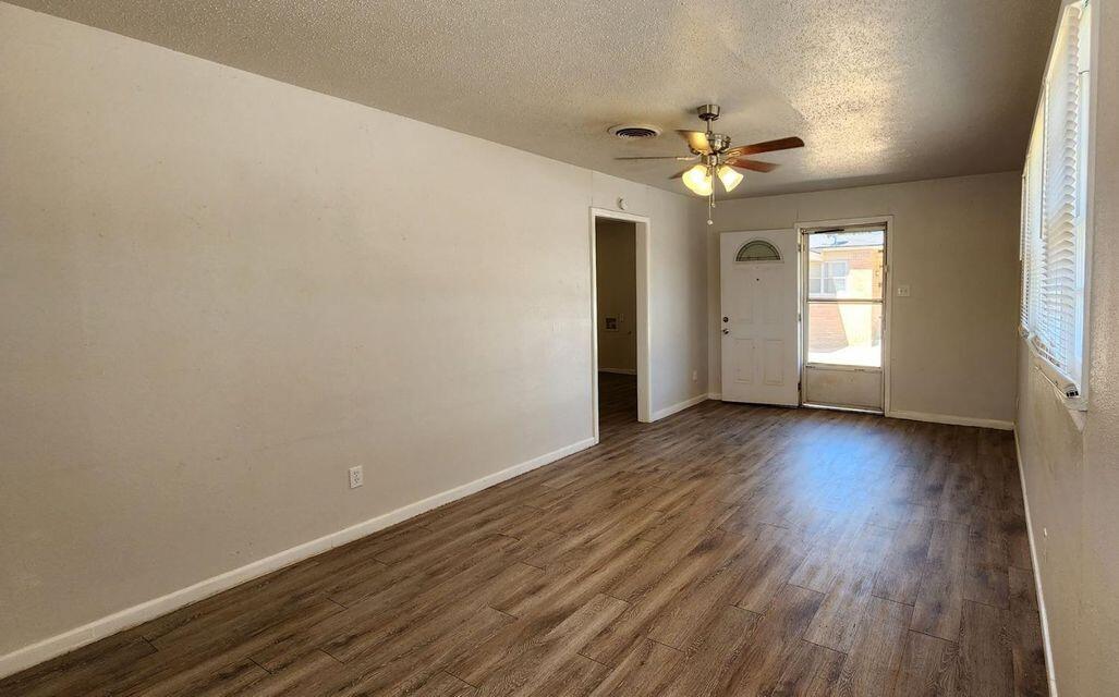 4401 31st Street Lubbock, TX 79410 - Photo 11 of 21 an empty room with wooden floor chandelier fan and windows