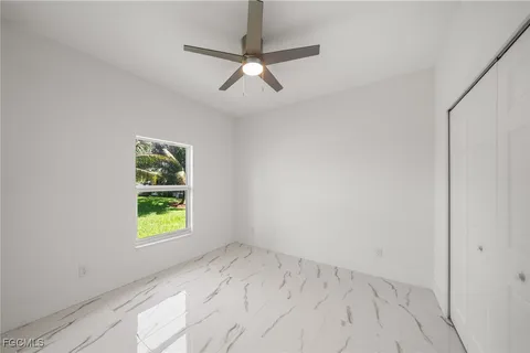 an empty room with a window and ceiling fan