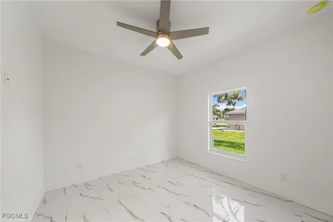 an empty room with window and ceiling fan