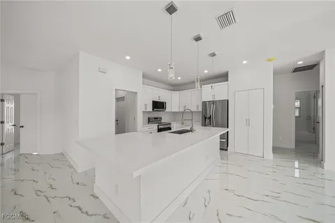 a large white kitchen with kitchen island a refrigerator a sink and a stove
