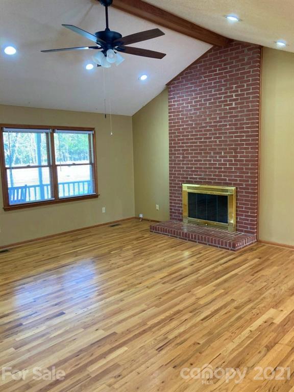1091 South Beersheba Road Clover, SC 29710 - Photo 8 of 23 an empty room with wooden floor fireplace and windows