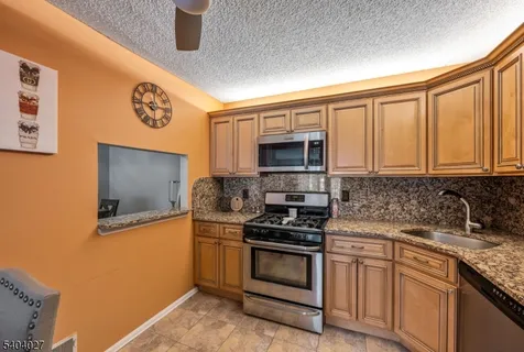 a kitchen with stainless steel appliances granite countertop a stove a sink and a microwave