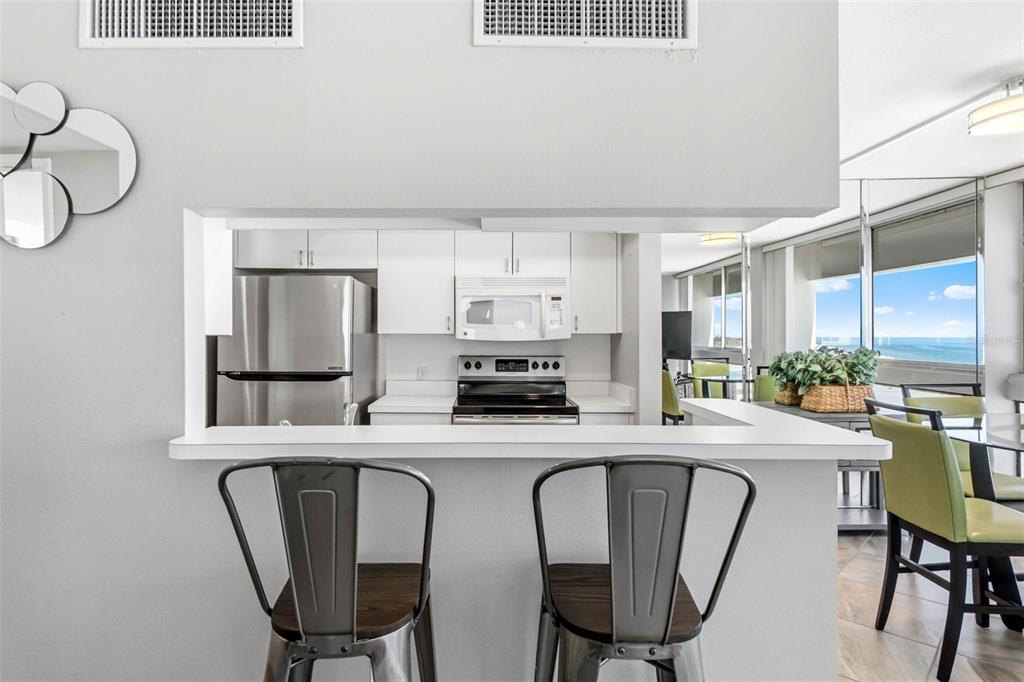 5966 Midnight Pass Road, Unit G113 Sarasota, FL 34242 - Photo 14 of 39 a kitchen with stainless steel appliances kitchen island granite countertop a dining table chairs and a refrigerator