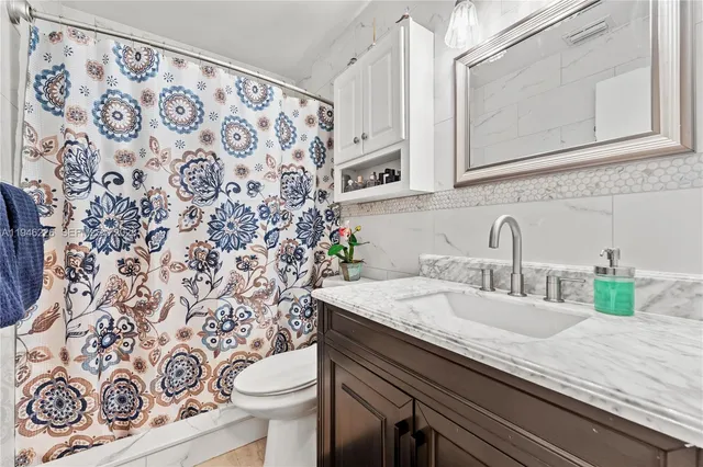 a bathroom with a granite countertop sink and a toilet