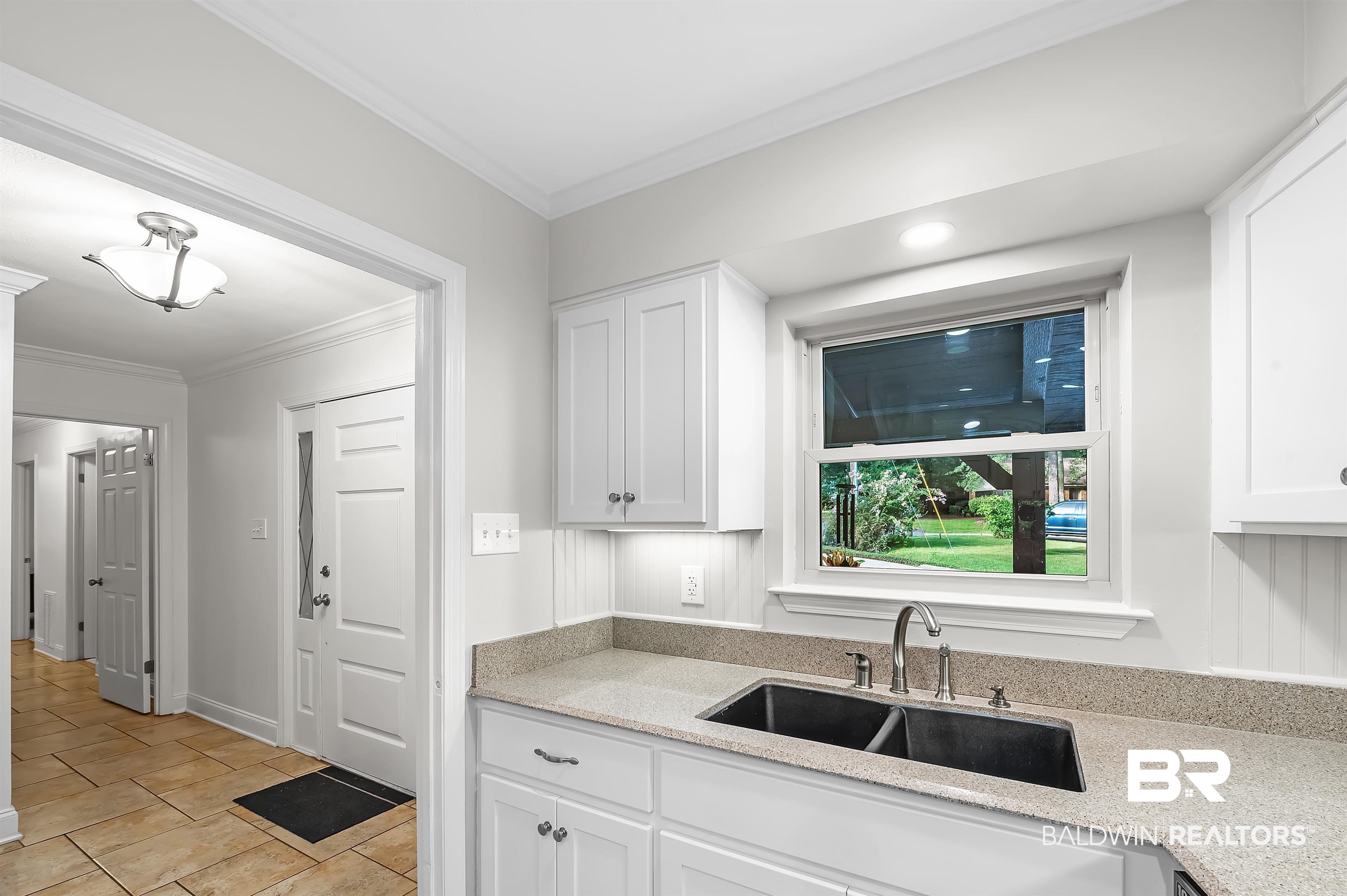 104 James Circle Daphne, AL 36526 - Photo 24 of 62 Kitchen featuring light tile patterned flooring, crown molding, white cabinets, light stone countertops, and sink