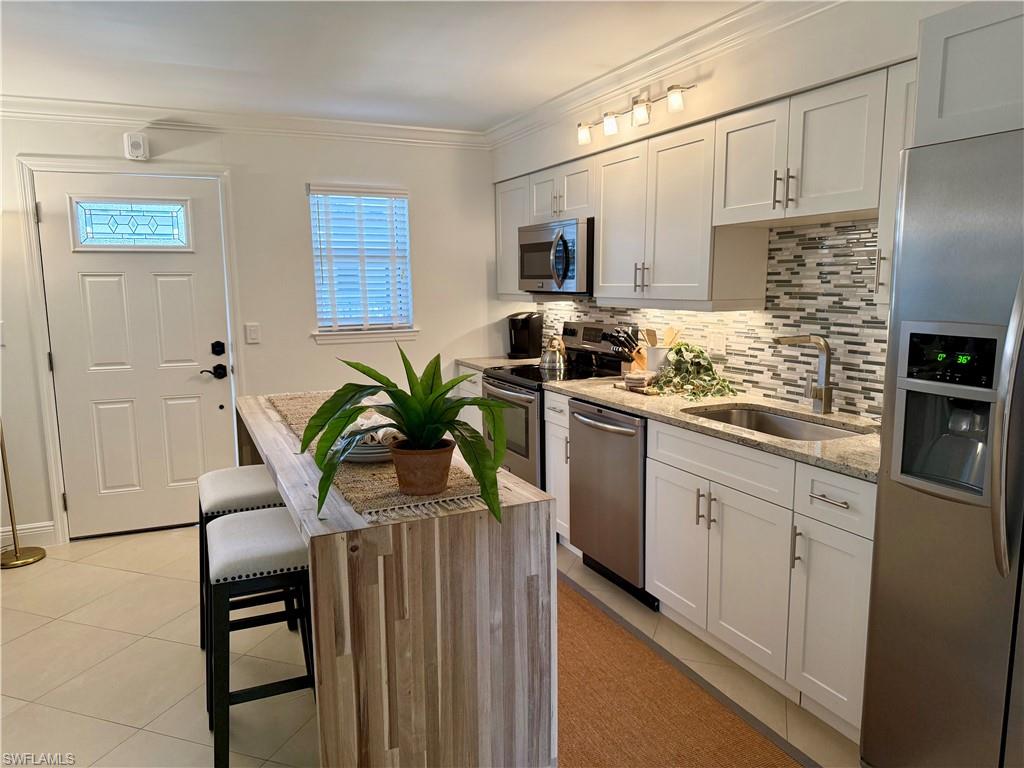 960 7th Street South, Unit 202 Naples, FL 34102 - Photo 5 of 16 a kitchen with stainless steel appliances a sink a table and chairs