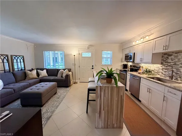a living room with furniture kitchen area and a wooden floor