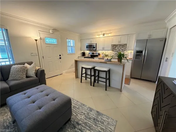 a living room with furniture a rug and kitchen view