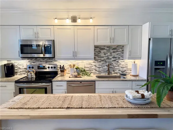 a kitchen with kitchen island granite countertop stainless steel appliances a stove refrigerator and microwave