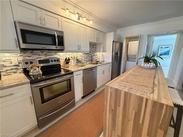 a kitchen with stainless steel appliances a stove microwave and sink