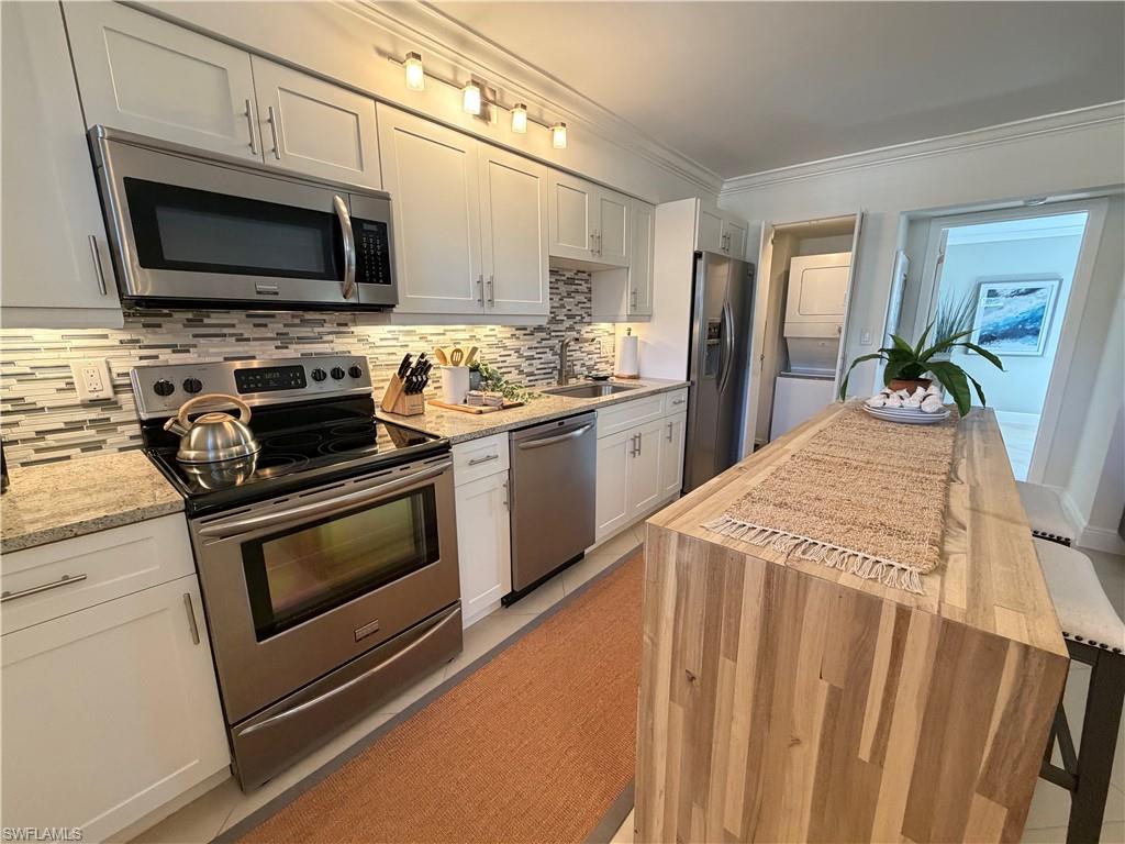 960 7th Street South, Unit 202 Naples, FL 34102 - Photo 9 of 16 a kitchen with stainless steel appliances a stove microwave and sink