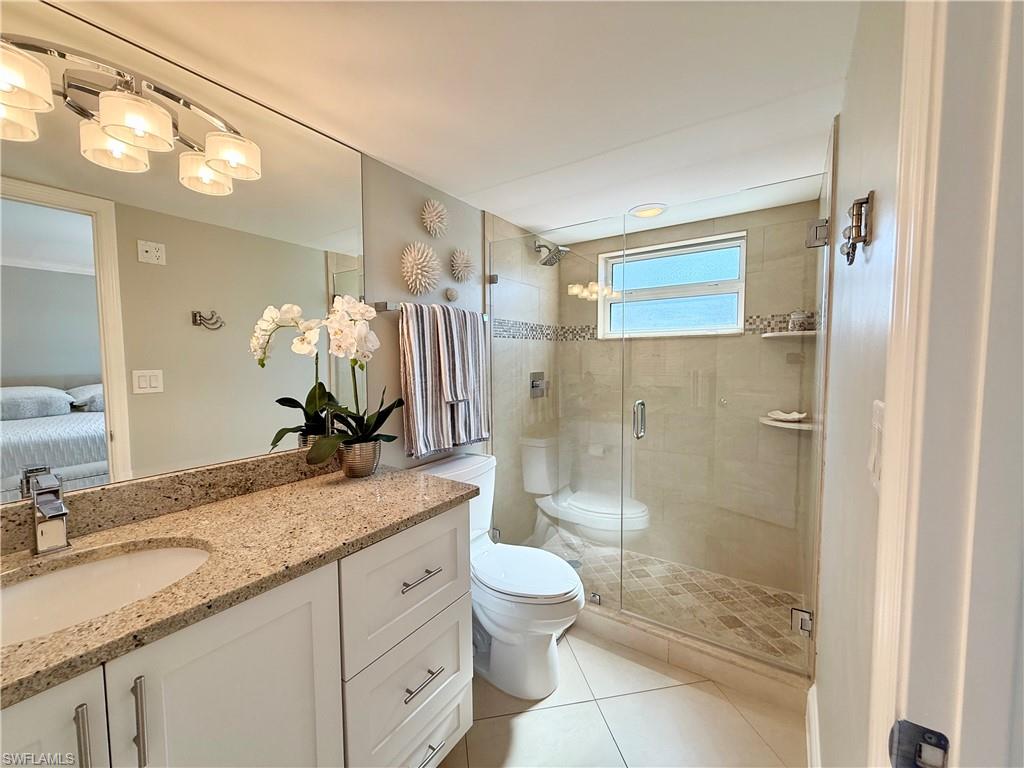 960 7th Street South, Unit 202 Naples, FL 34102 - Photo 10 of 16 a bathroom with a granite countertop sink a toilet a mirror and shower