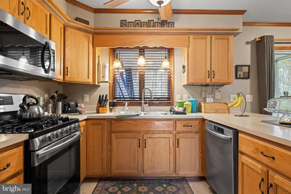 a kitchen with stainless steel appliances granite countertop a stove a refrigerator a sink a dining table and chairs with wooden floor