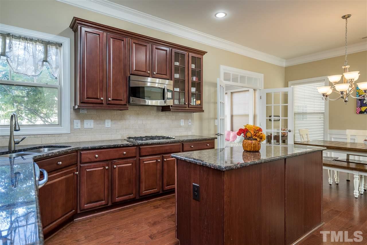 1411 Van Page Boulevard Raleigh, NC 27607 - Photo 14 of 26 a kitchen with kitchen island granite countertop wooden cabinets a sink and dishwasher