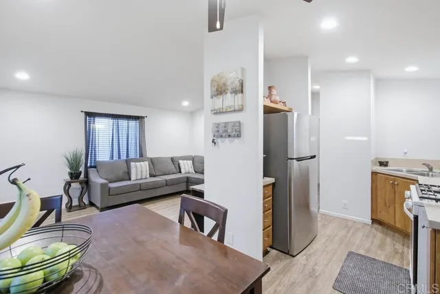 a living room with furniture a refrigerator and a dining table with wooden floor
