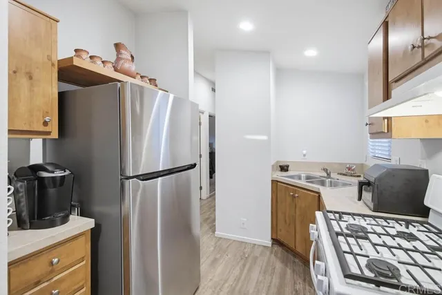 a kitchen with stainless steel appliances granite countertop a refrigerator a stove and a sink with wooden floor