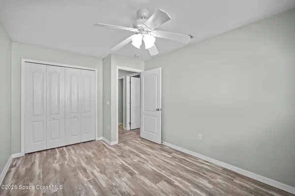 wooden floor in an empty room with a chandelier fan
