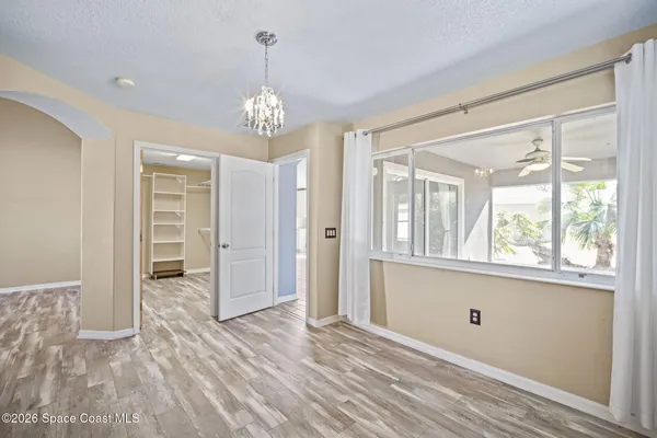 a view of empty room with wooden floor and fan