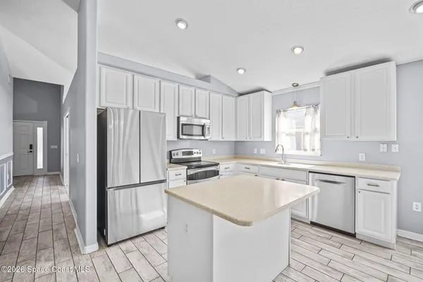 a kitchen with a sink a refrigerator a counter top space and cabinets