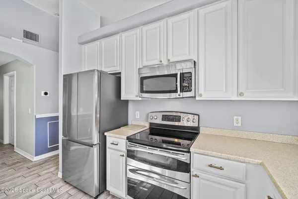a kitchen with stainless steel appliances white cabinets and a refrigerator