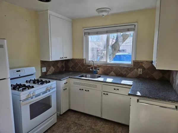 a kitchen with stainless steel appliances granite countertop a stove a sink and a microwave