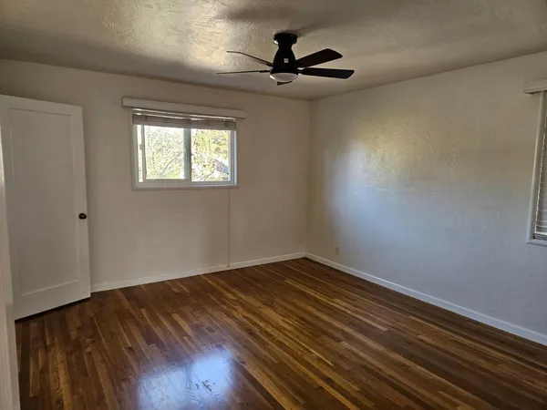a view of a room with wooden floor and a ceiling fan