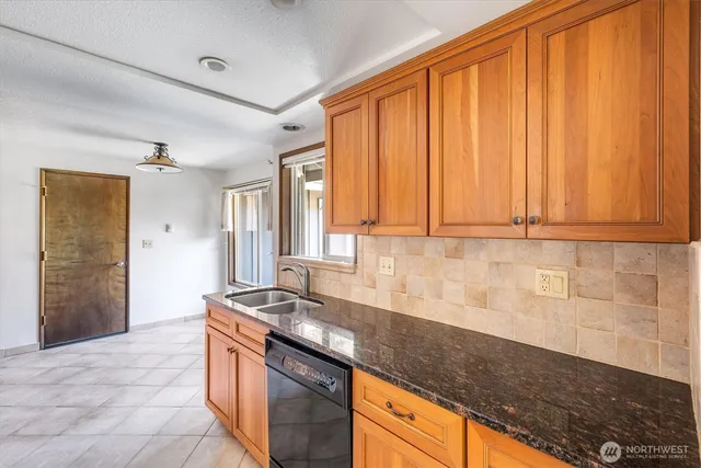 a kitchen with granite countertop a sink stainless steel appliances wooden floor and a counter top space