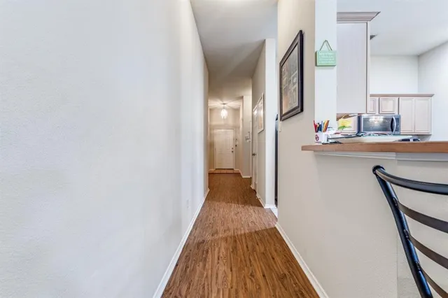 a view of a hallway with wooden floor and a bathroom