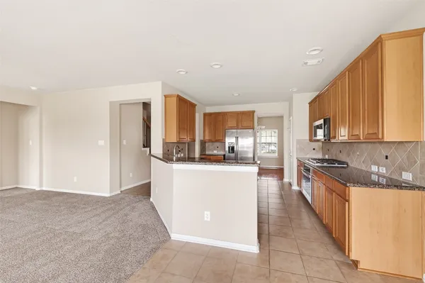 a large kitchen with stainless steel appliances granite countertop a refrigerator and a stove top oven