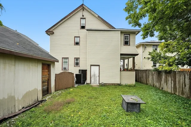 a view of backyard of house with wooden fence and a large tree