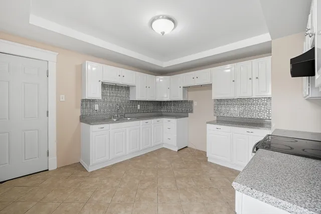 a kitchen with granite countertop white cabinets and white appliances