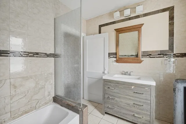 a bathroom with a granite countertop sink mirror vanity and bathtub